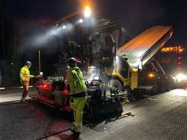 A road construction team works at night with the Cat AP500 asphalt paver